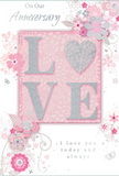 The anniversary card in this image radiates a quiet, timeless romance, combining soft pastel pinks, creamy whites, and brushed silvers that feel as tender as a freshly delivered bouquet on a doorstep in Edgware. Dominating the centre is the word LOVE, rendered in generous, raised lettering that has been delicately dusted with glitter, giving the surface a tactile sparkle that invites touch. The letters rest against a blush-pink background, the colour deepening slightly around the edges to create a gentle halo of warmth, as if lit from within. Encircling this central sentiment is an intricate illustration of flowers and trailing foliage, drawn in fine lines and shaded in tones of blush, ivory, and soft grey. The flowers recall stylized roses and spring blossoms, their petals opening outward in fluid shapes that mirror the natural curve of stems a florist might guide into place while assembling an anniversary arrangement for delivery near Edgwarebury Park or along the High Street. Slender vines and swirling flourishes weave between the blooms, adding motion and an almost musical rhythm to the composition, as though the flowers are drifting across the card in a slow, graceful dance. An elegant script message nestles among the floral swirls, expressing heartfelt anniversary wishes in flowing, understated lettering. The overall mood is serene and deeply affectionate, like the hush that falls after a couple unwraps a beautiful arrangement from their favourite local florist, a paper echo of soft petals, shared memories, and the quiet joy of another year celebrated together in Edgware.